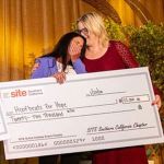 Two women stand together holding an oversized check for $22,100 made out to "Hoofbeats For Hope" at a SITE Southern California charities presentation..