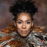 Princess Sarah Culberson wearing an elaborate garment made of various feathers in brown, black, white, and orange tones, posed against a muted brown background.