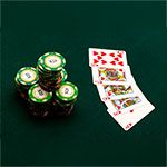 A stack of $25 casino chips sits next to a royal flush in hearts on a green felt table.